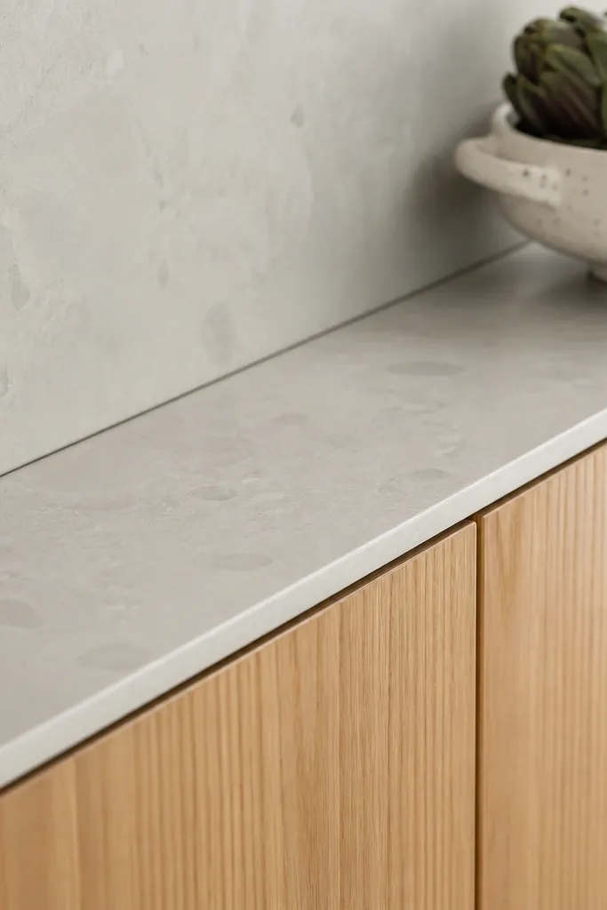 A side angle showing the gap between countertop and white oak cabinet faces. The backsplash is tight and there's a clean, even reveal line.