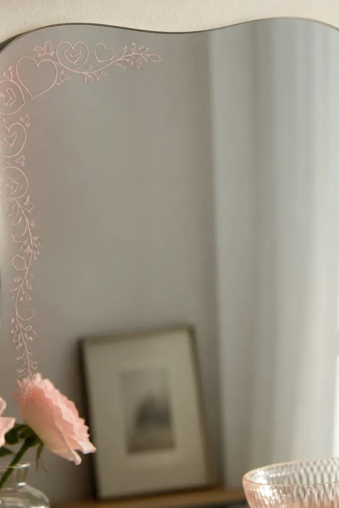 A mirror with a small corner border made of rose-quartz toned stickers. The border has a subtle heart pattern and runs only along one corner edge, not the whole mirror. The stickers look like frosted glass and blend into the mirror surface.