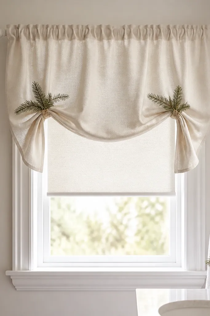 A small bathroom window with a short fabric valance in cream linen look, mounted on a small tension rod, with a subtle evergreen tie-back and a simple roller shade underneath.
